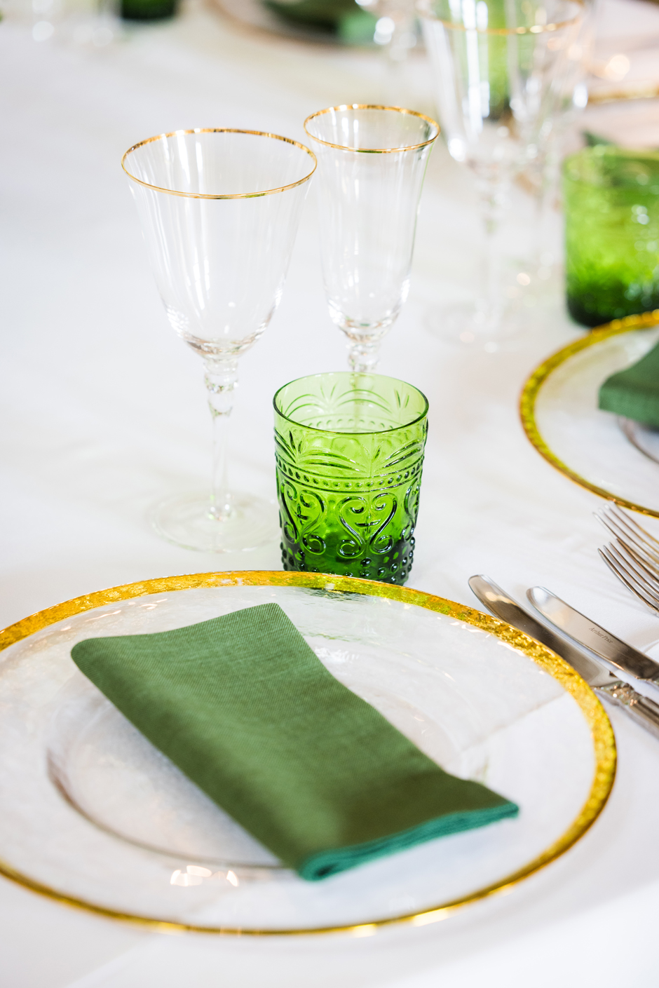 Green water glass with white Essential linen, evergreen Gelato napkin, gold trim charger plate & gold trim glasses