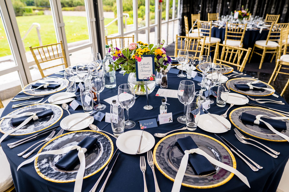 Navy Essential table linen, Gold Trim charger plates with Navy Essential napkin tied with ribbon