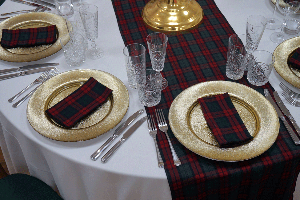 White Essential table linen, Lindsay Tartan runner and napkins, Gold Starburst charger plates paired with Cut Crystal glasses