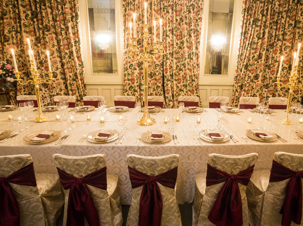 St. Tropez table linen and chair covers paired with Burgundy Taffeta seat ties and Gold candelabras