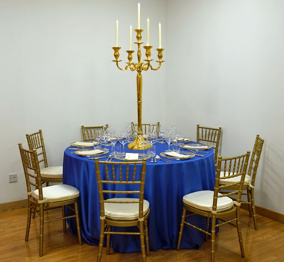 Electric Blue Faux Silk table linen, Gold Chiavari Chair with Vanilla Milano seat pads,Gold Candelabra, Gold Beaded charger plates paired with Vanilla Milano napkins