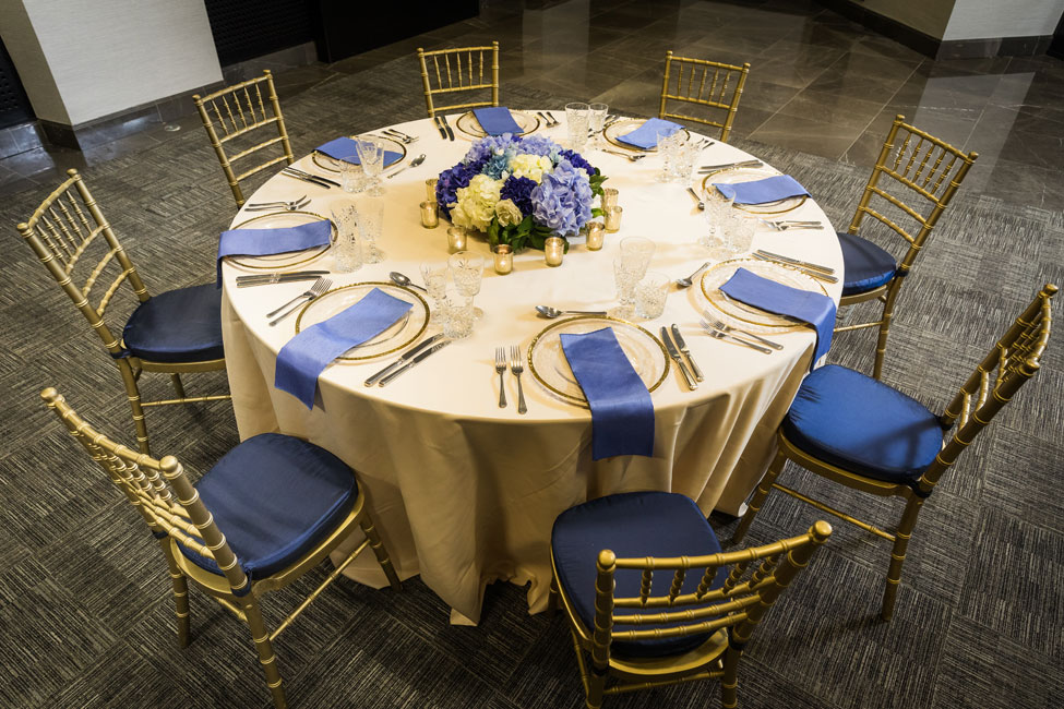 Styling featuring Nude Verona table linen, Gold Trim charger plates paired with Electric Blue Faux Silk napkins, Gold Chiavari Chairs with Midnight Blue Taffeta seat pads